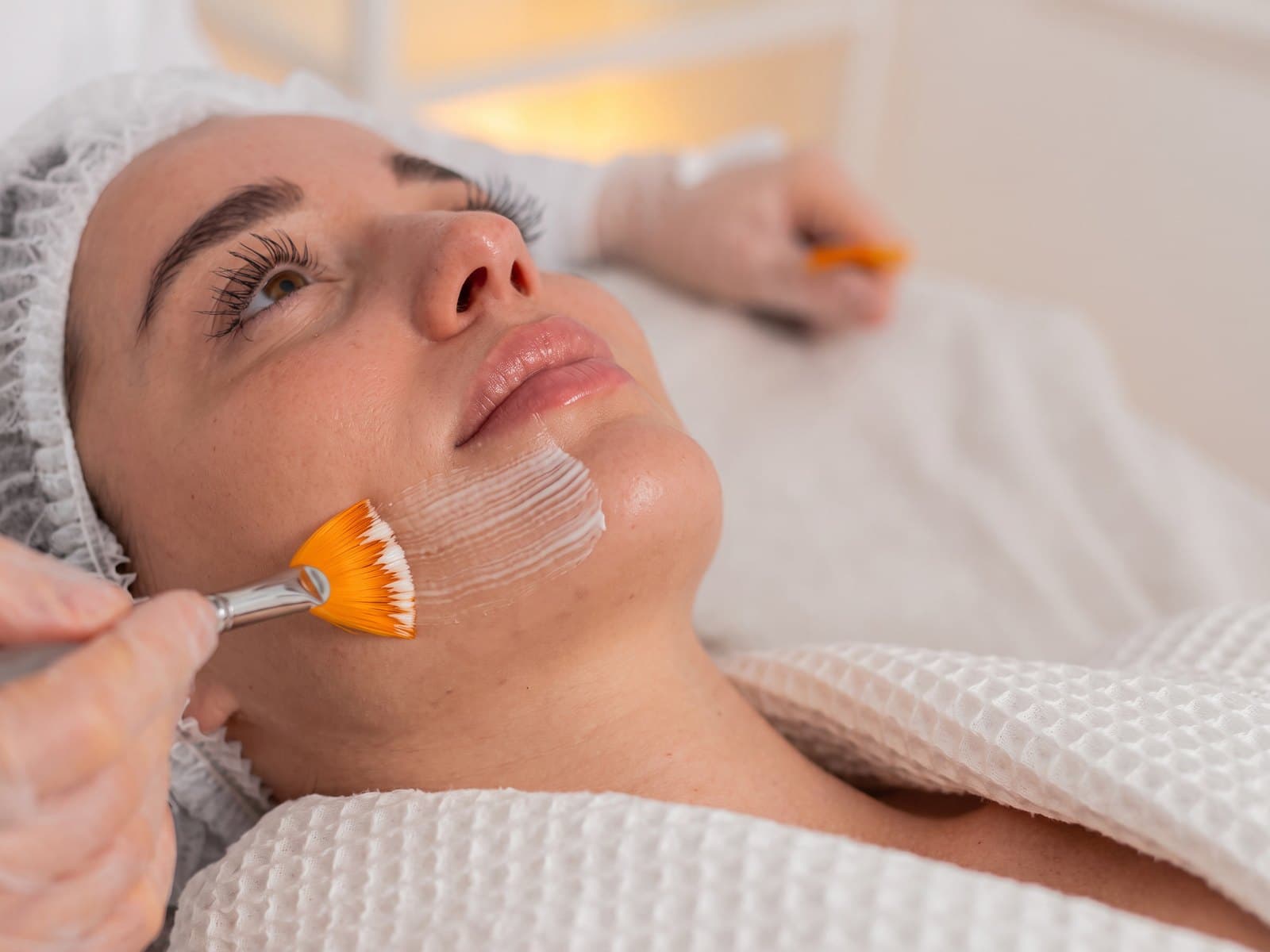 Aplicação de peeling químico com pincel no rosto de uma paciente